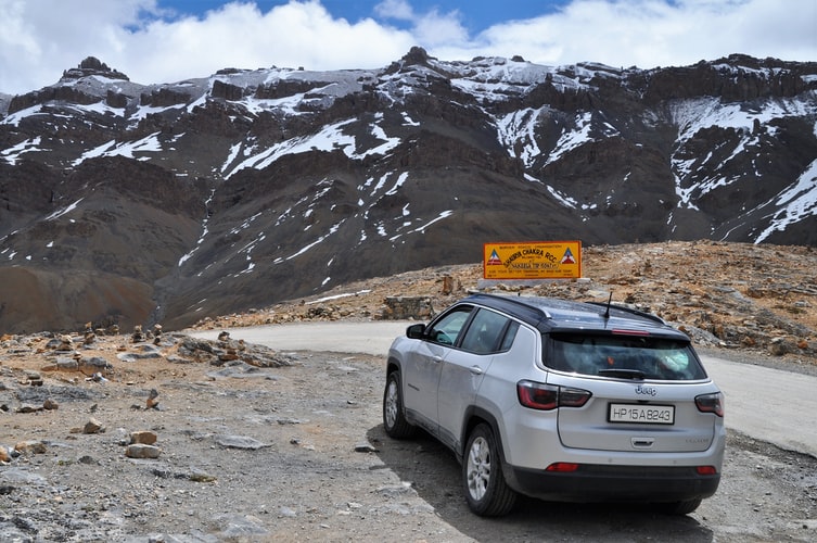 White Jeep Compass in front of snow-peaked mountain range