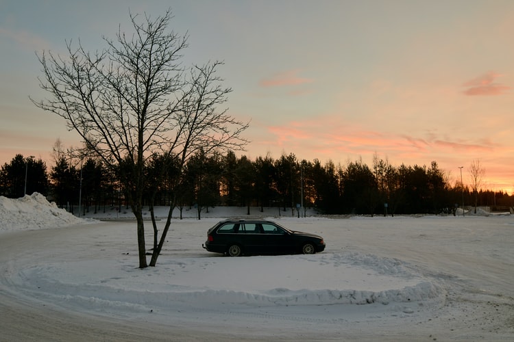car in snowy parking lot during sunset