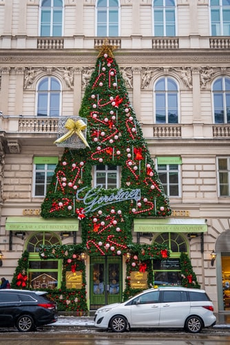 christmas tree decoration on building with cars parked in front